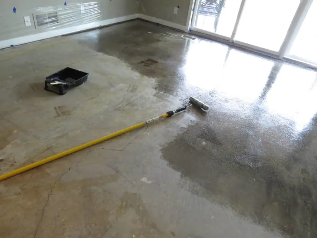Almost halfway done staining the concrete floor, the roller I used and the paint tray laying on the floor.