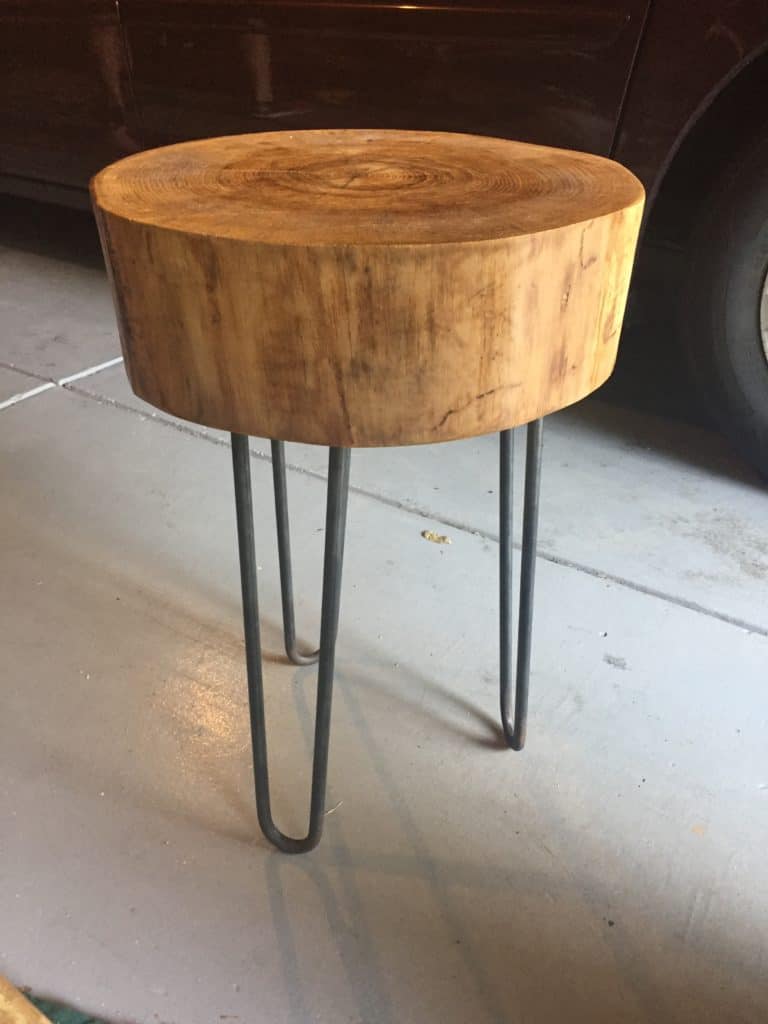 On my garage floor is the completed side table made from a tree stump.