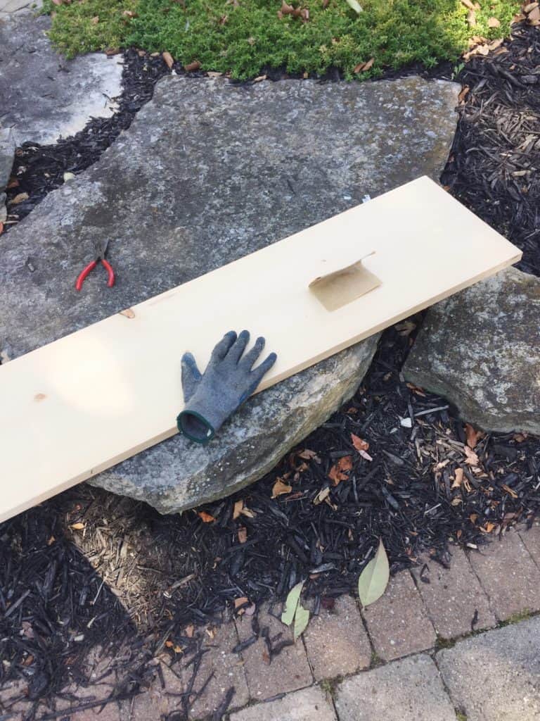 My wood is sitting on a rock in my front yard and I am sanding the wood smooth.