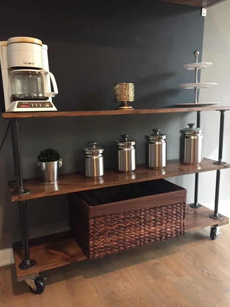 The finished industrial shelves that have silver canisters and a basket on the bottom shelf.