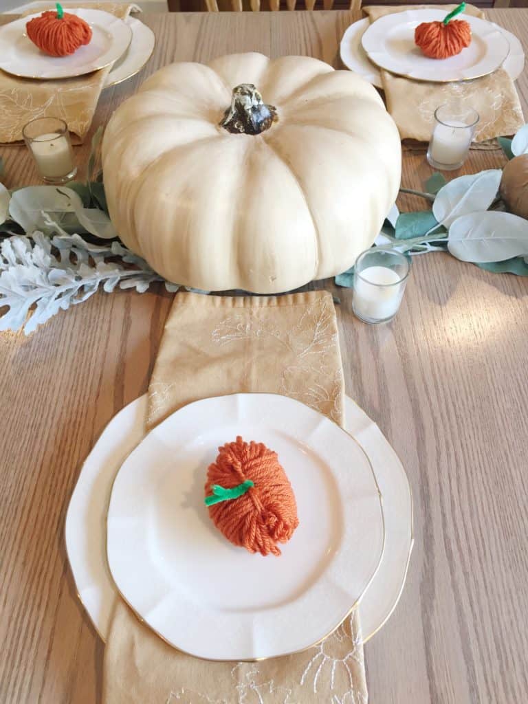 The table is set with the centerpiece, white votive candles and my dishes with yarn pumpkins on the top plate.