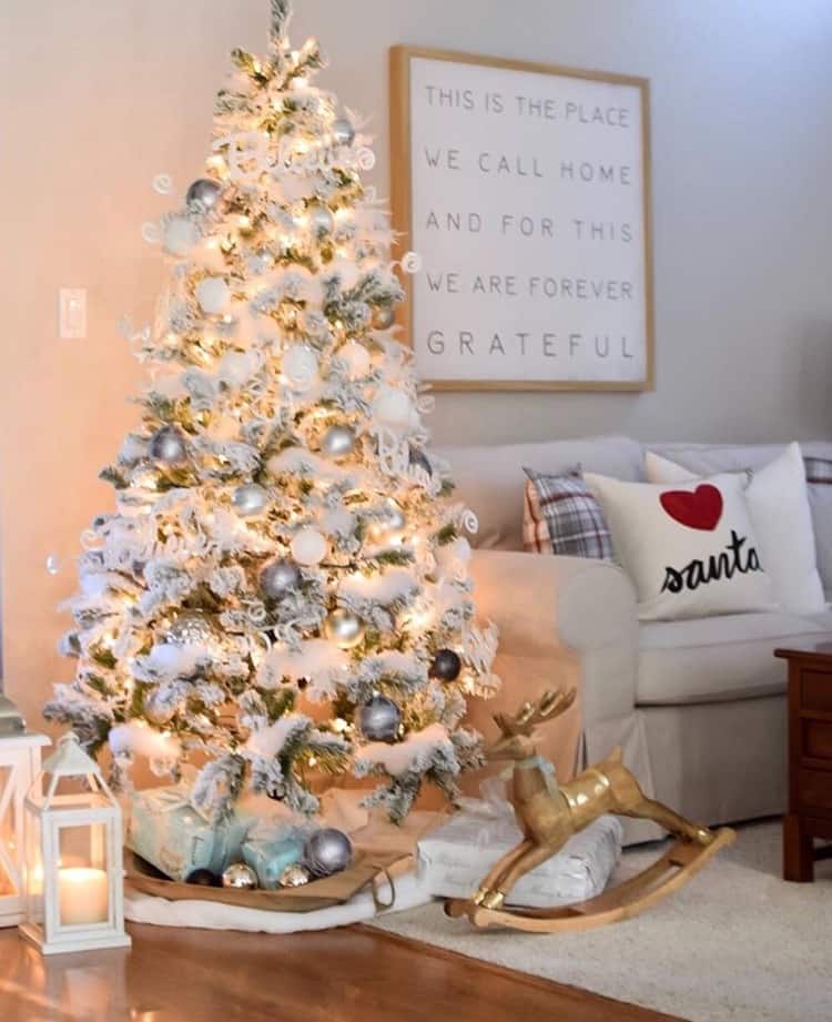 A flocked Christmas tree with white fluffy garland and white and silver balls.