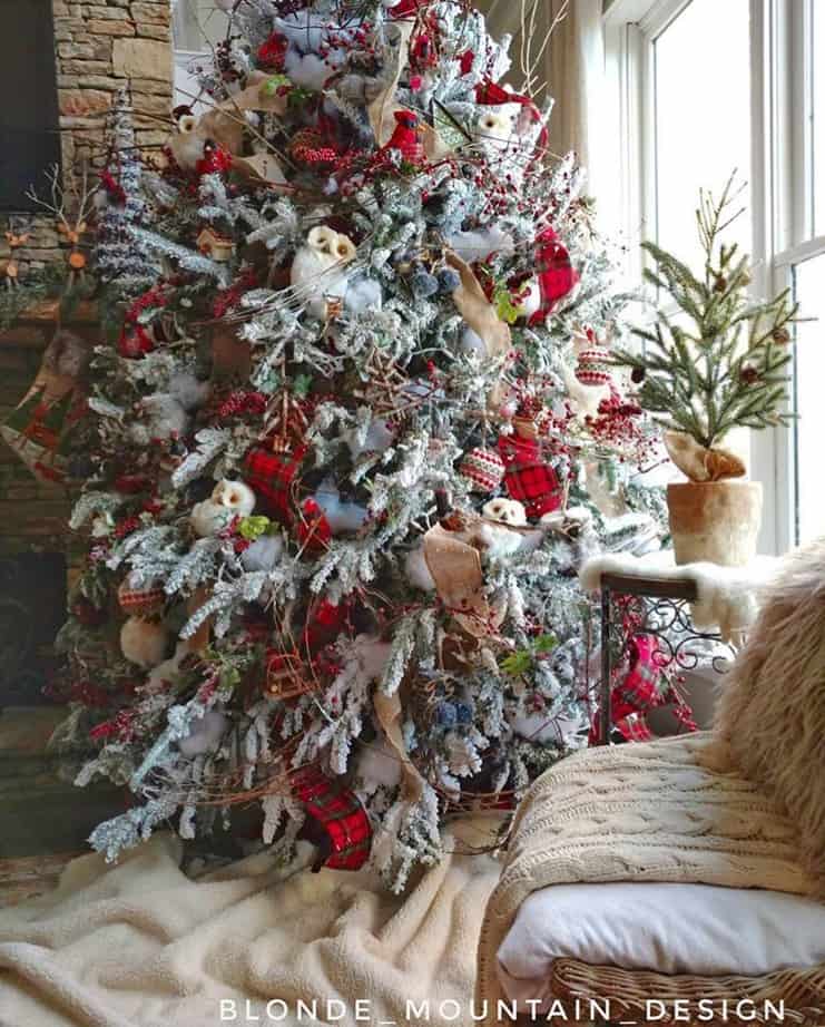 A flocked Christmas tree that is decorated with owls and other items from nature.