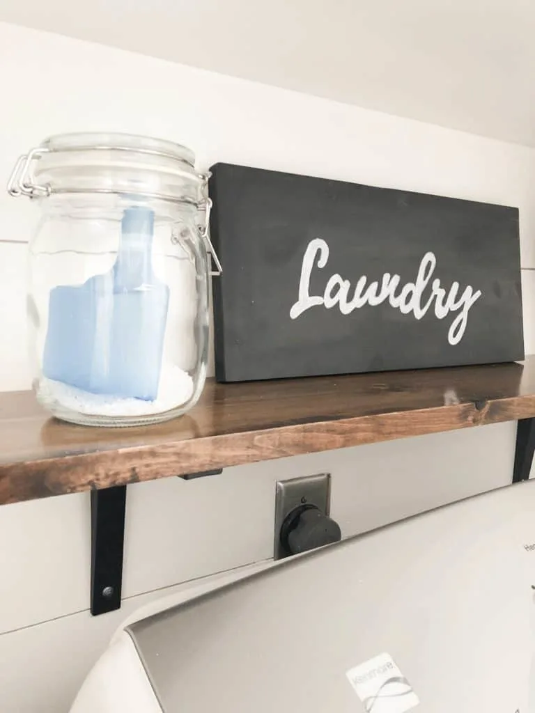 This DIY laundry sign with chalkboard paint sits on the shelf above the dryer.