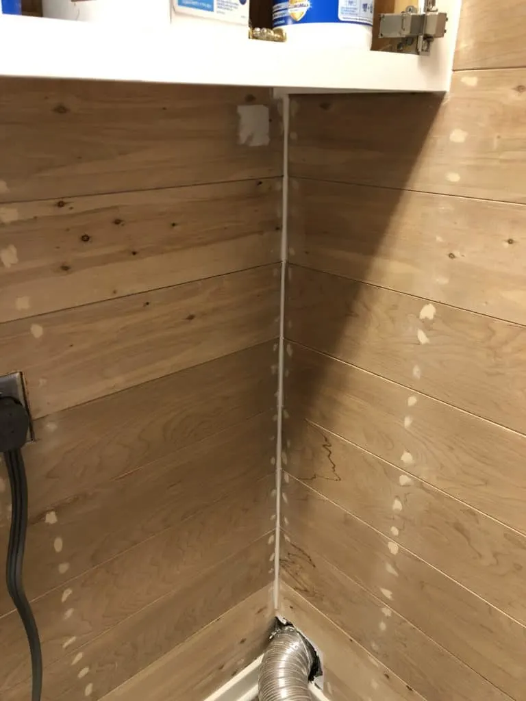 This shows the raw shiplap with wood putty on the nail holes and caulk in the corner.