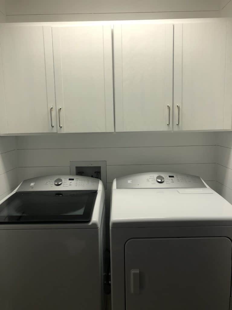 This is a laundry room with white shiplap walls.