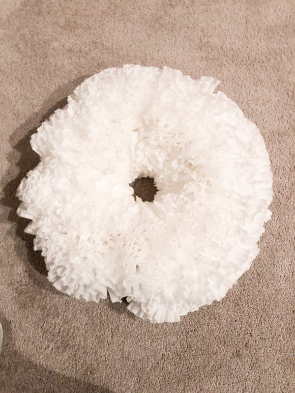 A coffee filter wreath sitting on my carpet about 80% finished.