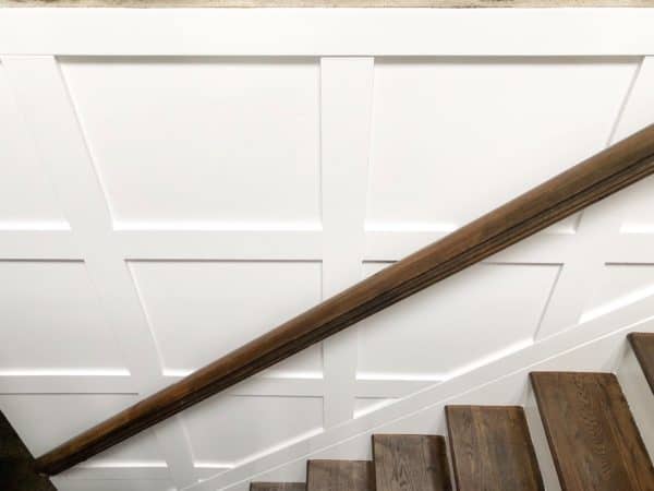 The finished box molding, white walls, brown stained stairs and a brown railing.