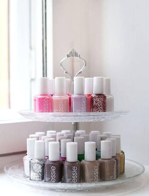 A tiered tray with pretty nail polish on it in rows.