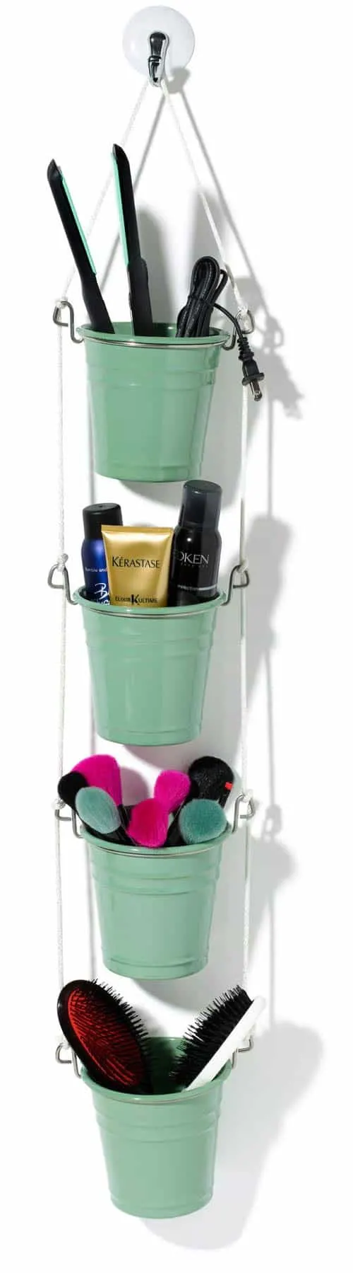 four small buckets hanging vertically holding hair brushes, makeup brushes, hair tools and hair products.