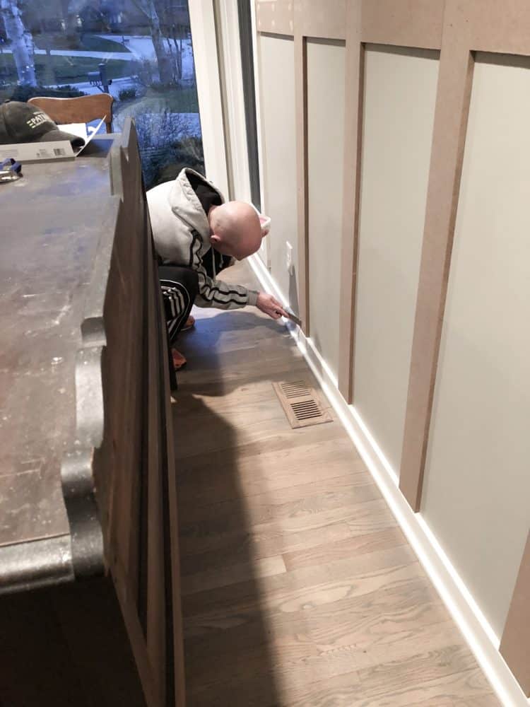 DIY Board and Batten, my husband applying wood putty to the nail holes.