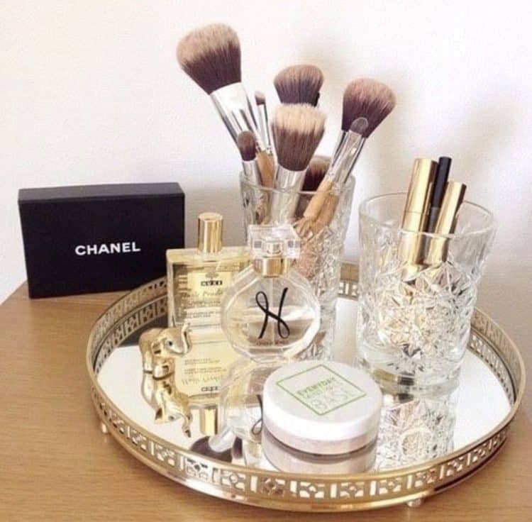 A gold and glass tray with beautiful perfume bottles and a chanel box behind it.
