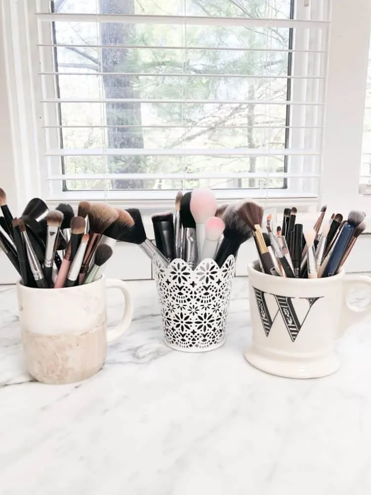 Makeup brushes stored in pretty mugs.