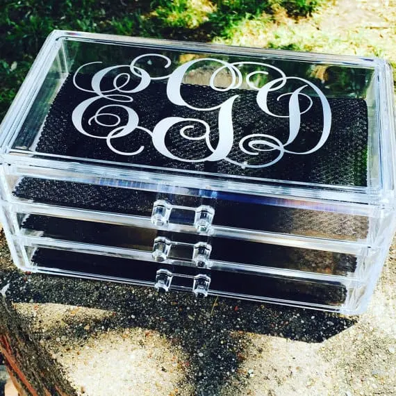 Acrylic box with drawers and a monogram on top.