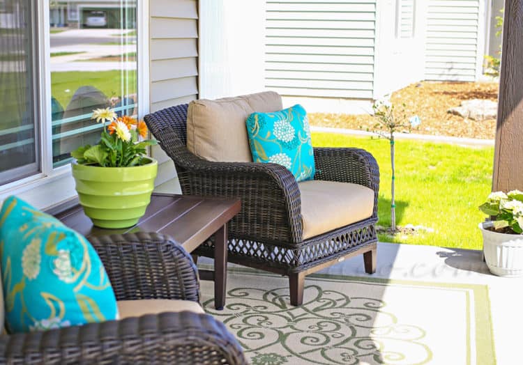 Two brown chairs with beige cushions and a table in between with flowers on it.