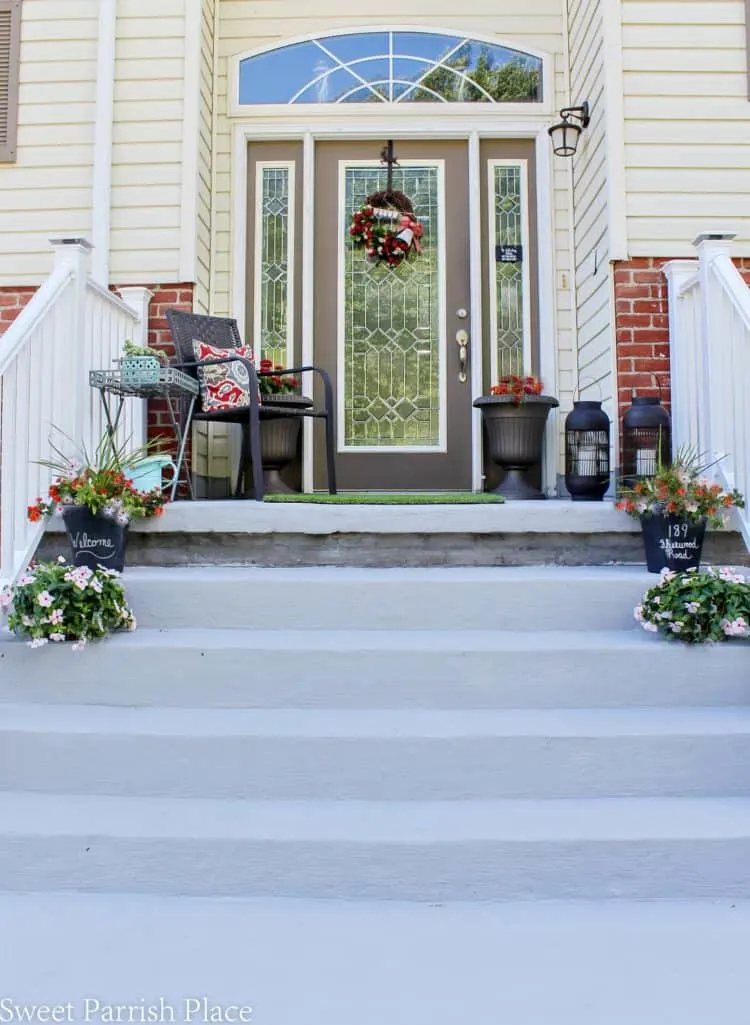 A front porch that is elevated with lots of steps and flower pots on each step on either side.