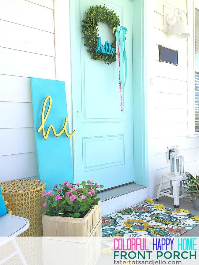 A front porch with a bright light blue door and a sign that says hi.