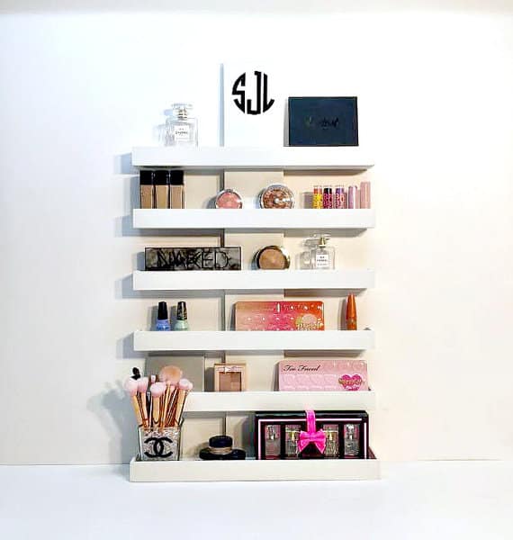 a set of 5 White shelves designed to sit on top of a desk holding different makeup products.