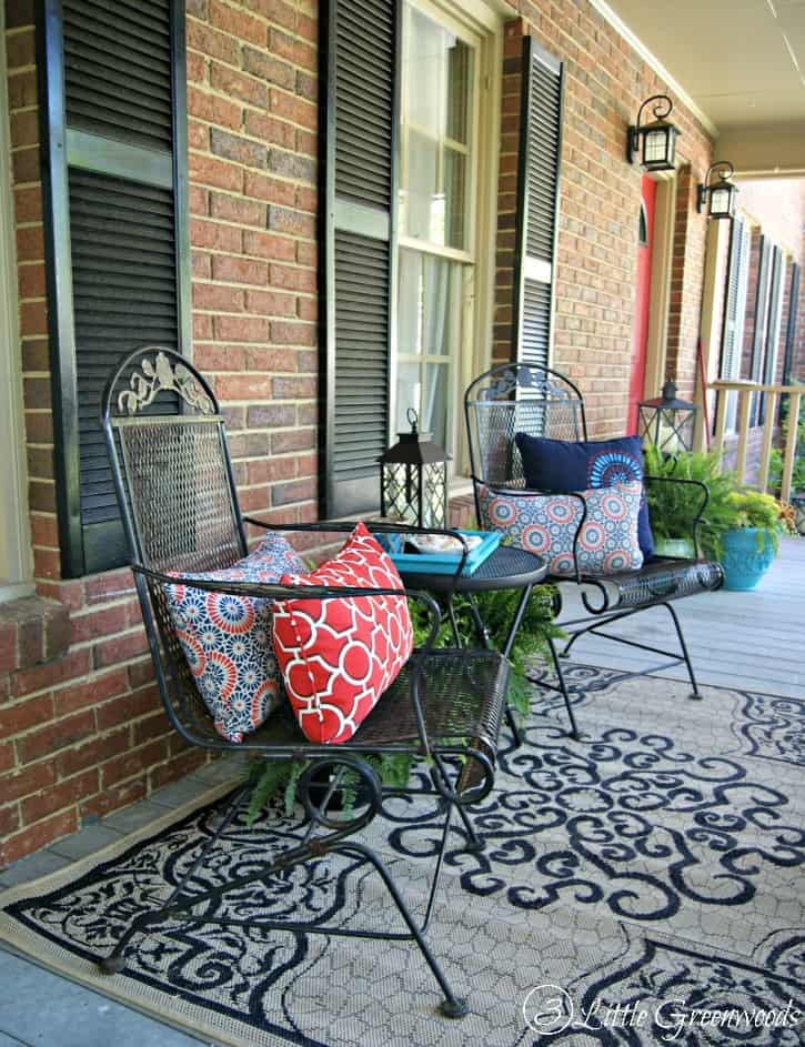 A front porch with metal chairs and geometric throw pillows that are multi-colored.