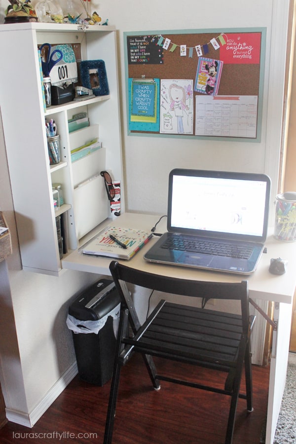 A small desk area that is a command center with a foldable desk top and when unfolded shows organization and a large cork board.