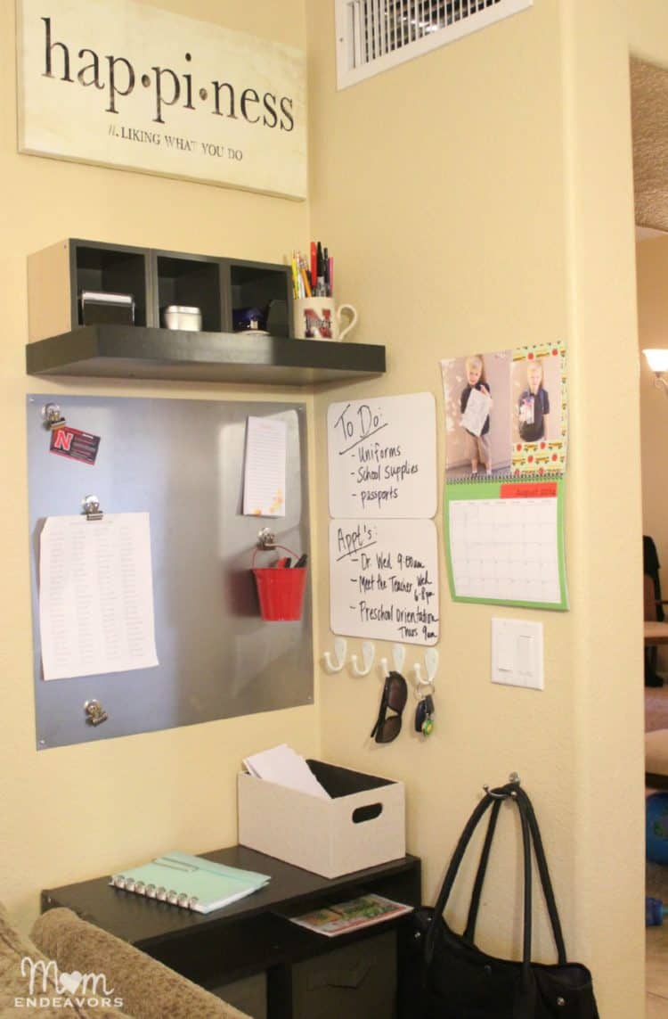 A command center in a family room with a calander, a metal square for magnets and dry erase boards.