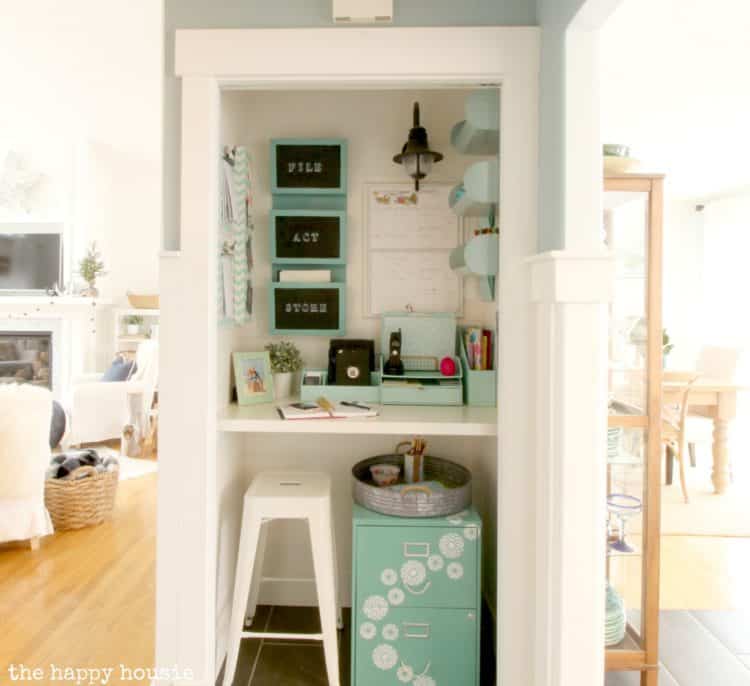 A closet converted to a command center with turquoise decor, a shelf that acts like a desk and a stool.