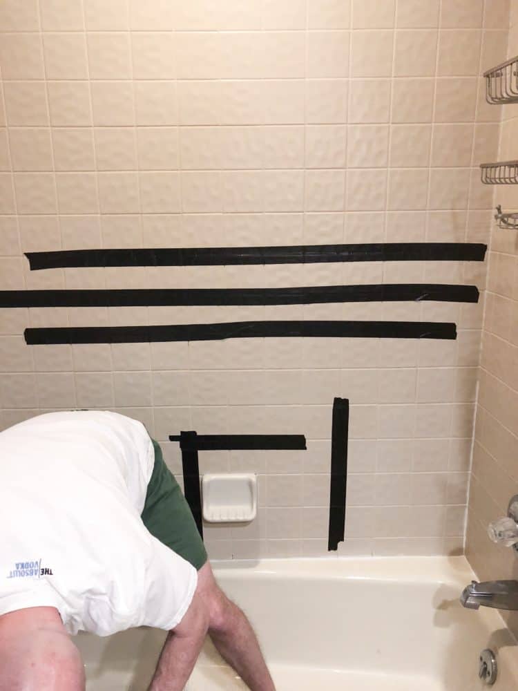 My daughters shower wall with black duct tape on beige tiles.