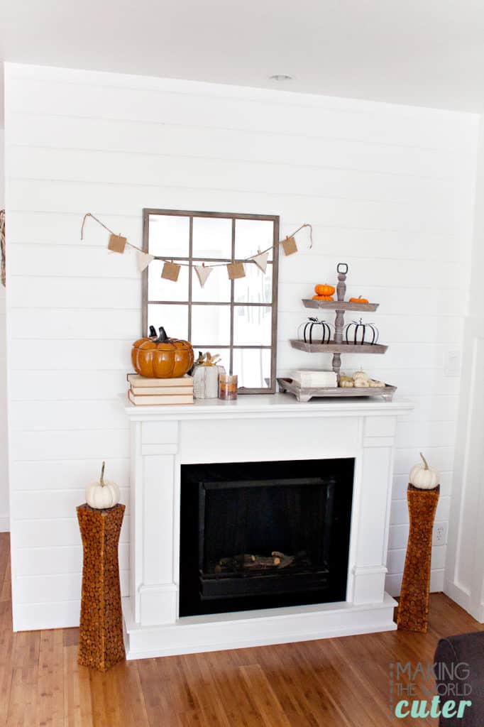 A white mantel with a tired tray on top with pumpkins on it.
