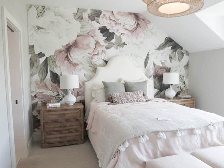 A girls bedroom with a floral mural on the headboard wall.