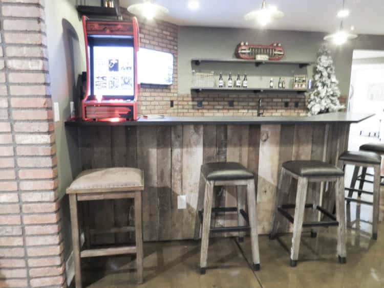 A bar in the home with wood on the bar counter and brick on the wall.