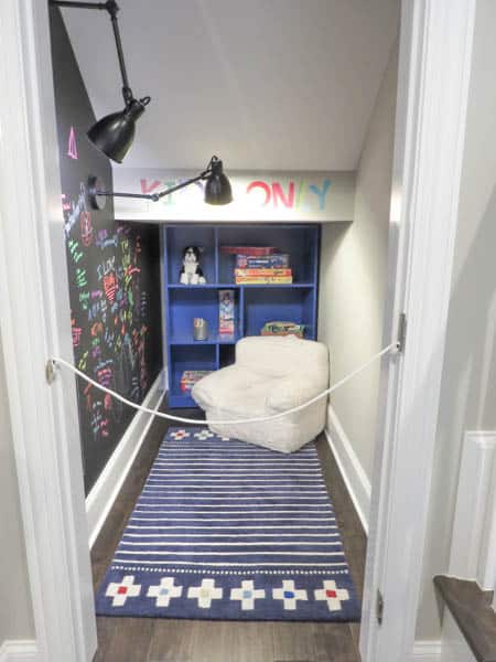 A nook under the stairs with a chalkboard accent wall.