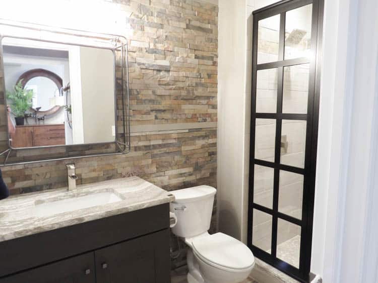 A bathroom with stacked stone tile on the wall behind the vanity.