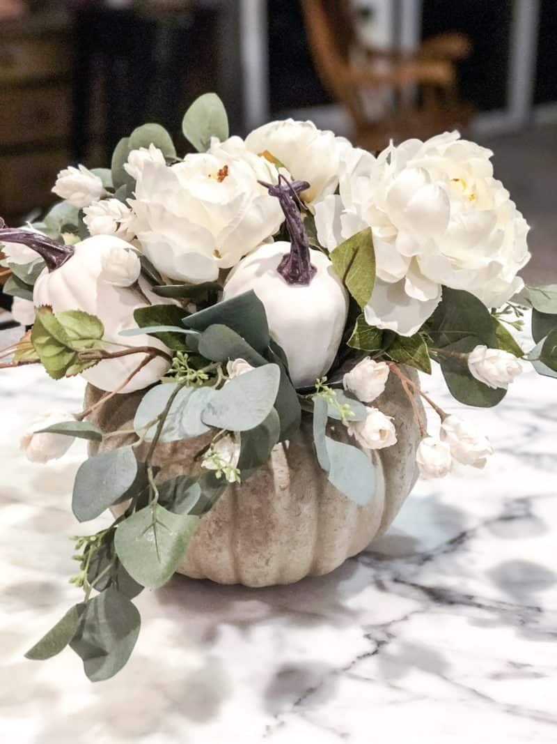 A pumpkin flower arrangement with small white flowers, white peonies and eucalyptus.