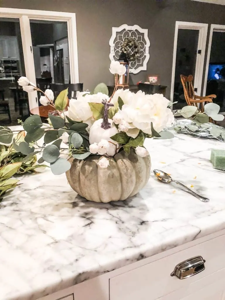 Adding little white flowers to drape over the edges of the pumpkin flower arrangement.