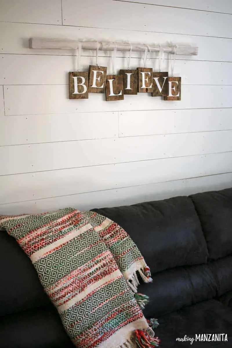 Farmhouse Christmas Decor, a Believe sign hanging on a spindle above a couch