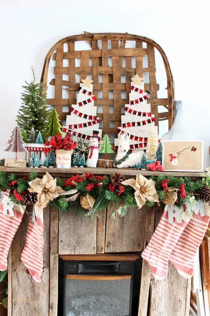 Farmhouse Christmas Decor a beautiful reclaimed wood mantel with DIY wood christmas trees, stockings and a bunch of christmas trees.