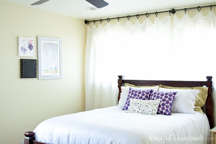 This simple bedroom has white curtains hanging on clips.