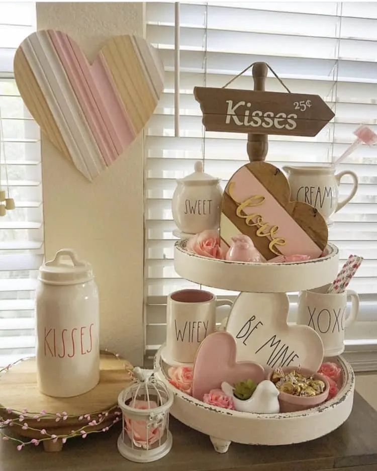 A tiered tray with Rae Dunn pottery saying Be mine, XOXO, wifey and kisses.