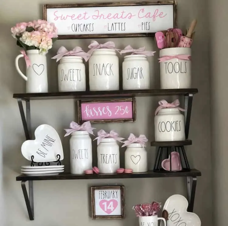 A display of Rae Dunn with pink accents and farmhouse signs.