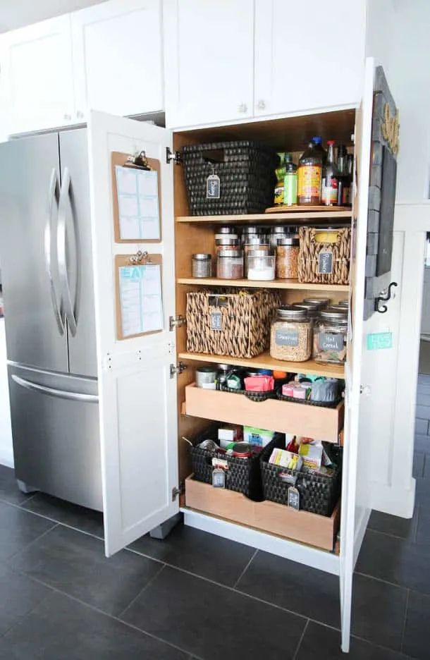 A pantry with baskets, glass jars with labels and pull out drawers.