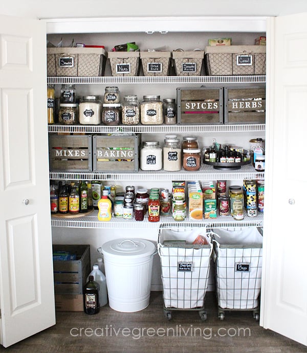 A pantry that is organized with glass jars with labels, baskets with labels and wood crates with labels.