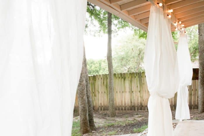 White curtains hanging from a cover patio.