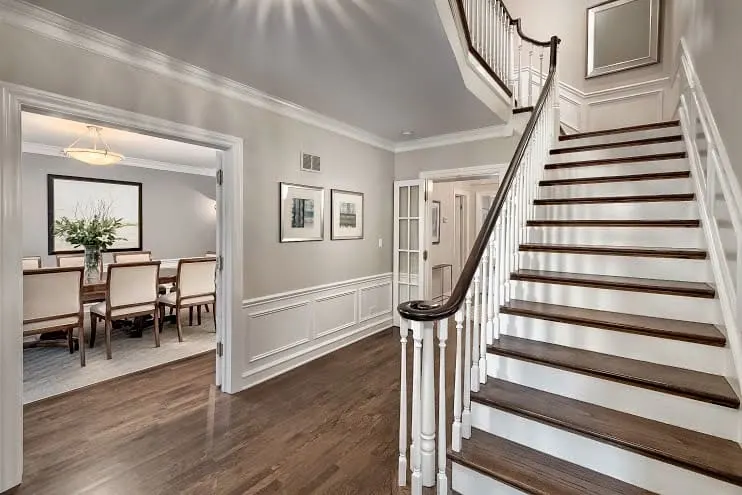 Edgecombe Gray Paint color in an entryway with a grand staircase and wainscotting.