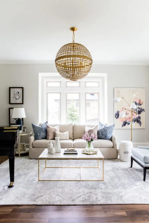Classic Gray Greige Paint Color in a family room with a beige couch and a gold and marble coffee table on a gray rug.