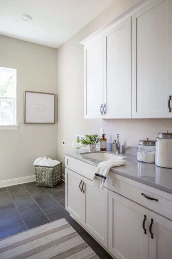 Worldly Gray Greige Paint Color in a Laundry Room with white cabinetry and gray slate tile floors.