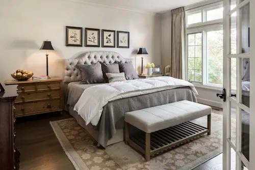 Useful Gray Greige Paint Colors in a family room with an upholstered headboard, tons of windows and gray bedding.