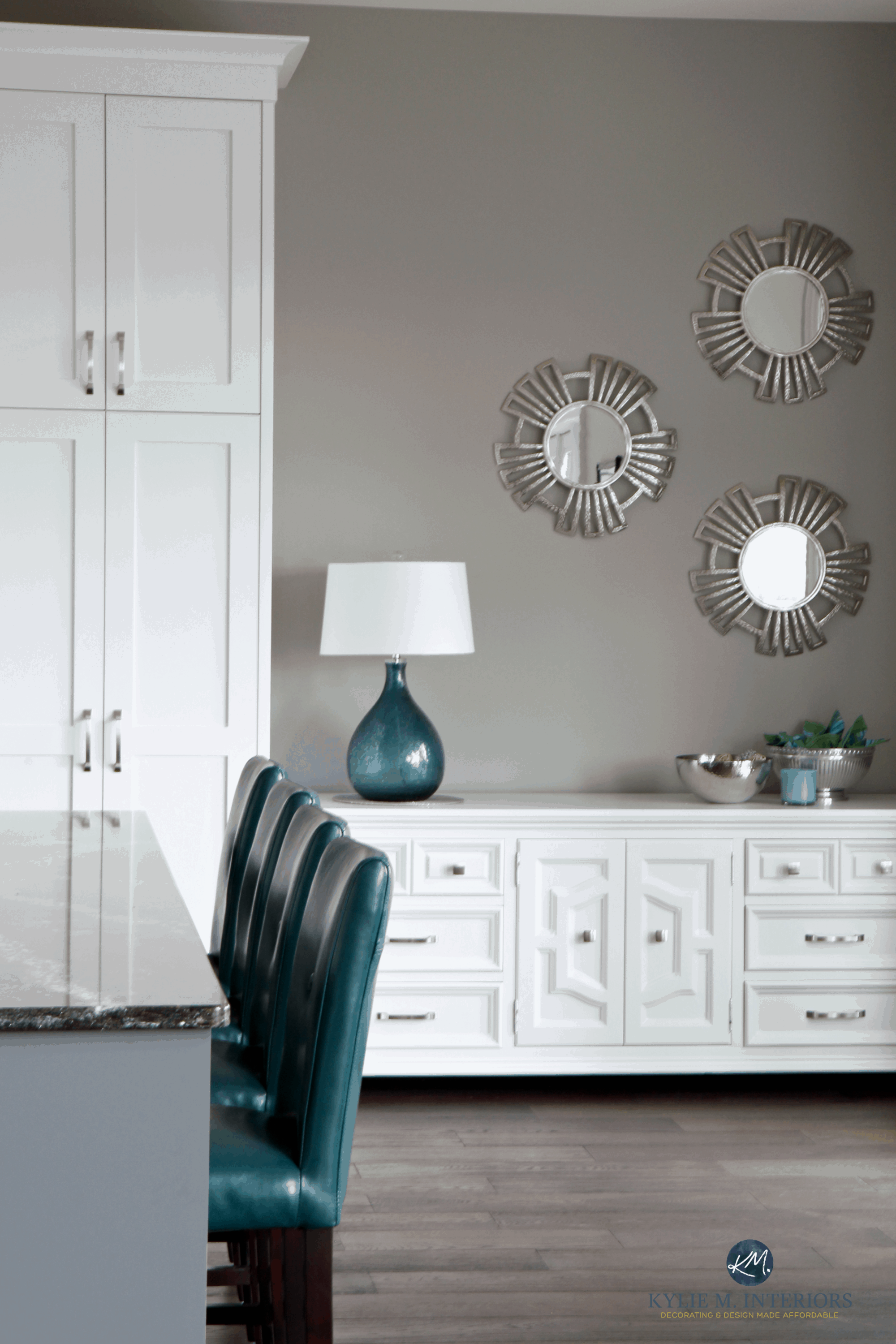A dining room with dark greige on the walls, white furniture, and teal accents in the accessories.