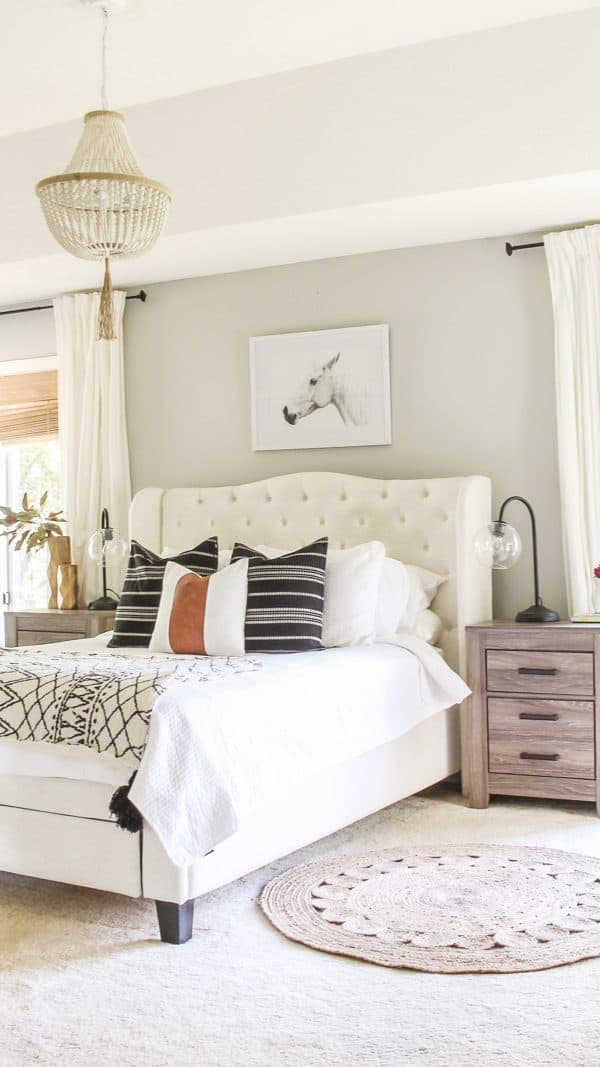 Repose Gray Greige Paint Color in a bedroom with a cream upholstered headboard and gray stained nightstands.