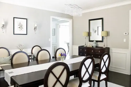 Revere Pewter Greige Paint Color in a dining room with white wainscotting.