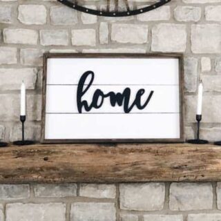 A farmhouse sign on my mantel made using shiplap and the word home on it.